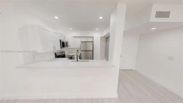 a view of a big room with wooden floor and windows
