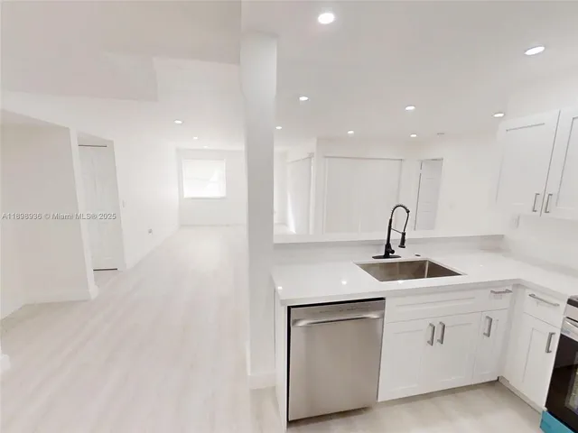 a kitchen with white cabinets appliances and sink