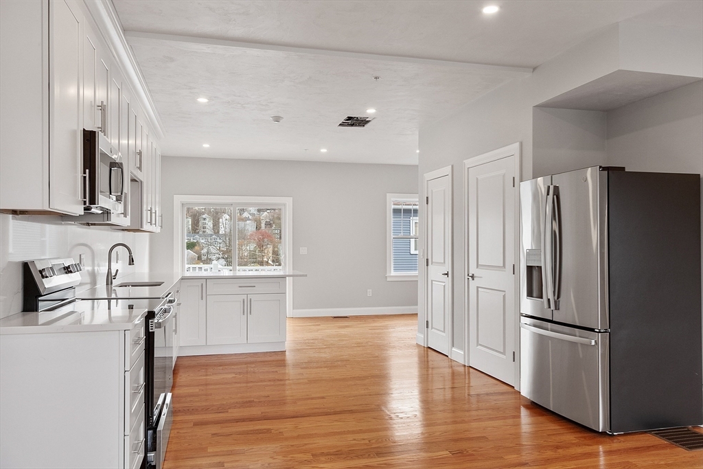 10 Windsor Street, Unit B Worcester, MA 01605 - Photo 12 of 38 a kitchen with stainless steel appliances a refrigerator sink and wooden floor