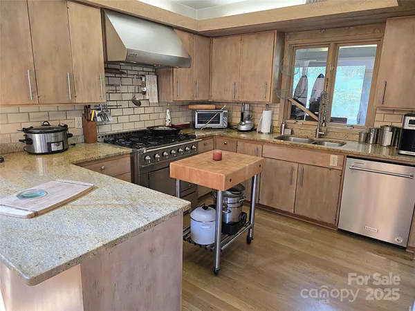 a kitchen with stainless steel appliances kitchen island granite countertop a sink dishwasher stove and refrigerator