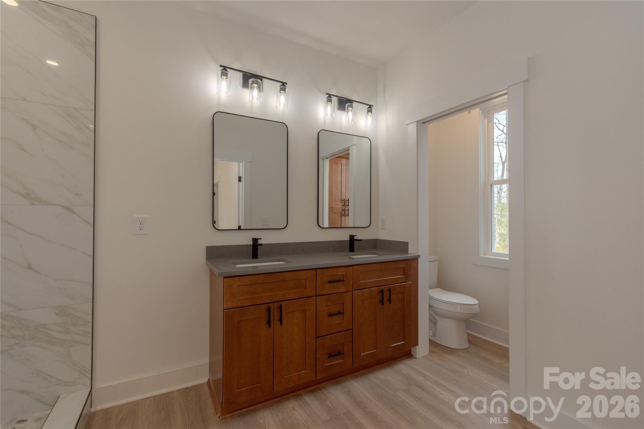 10303 Sycamore Road, Unit 90 Norwood, NC 28128 - Photo 30 of 42 a bathroom with a double vanity sink a toilet and a mirror