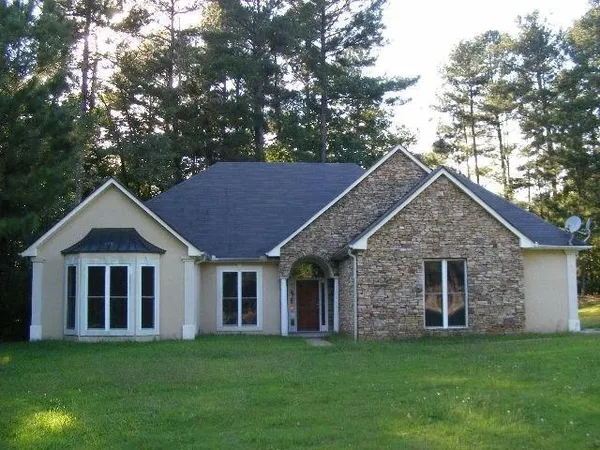 a view of a yard in front of a house with plants and large tree