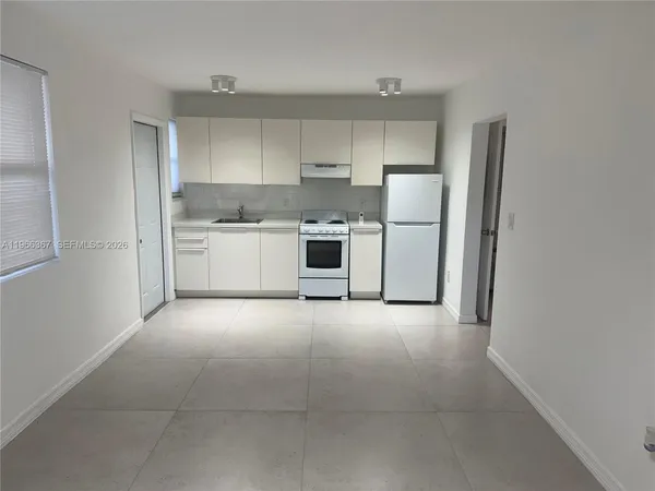 a kitchen with a refrigerator and white cabinets