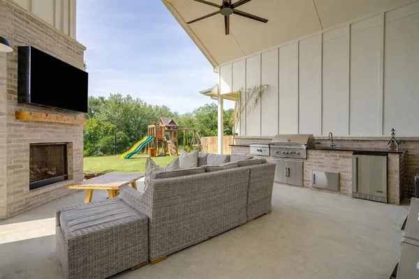 a living room with stainless steel appliances furniture a fireplace and a flat screen tv