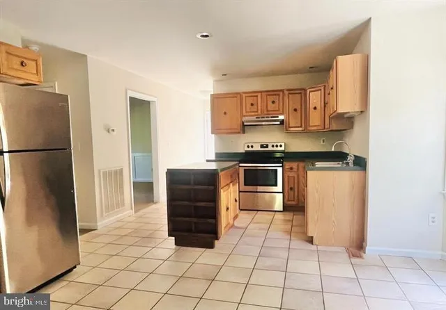 a kitchen with stainless steel appliances granite countertop a refrigerator and a stove top oven
