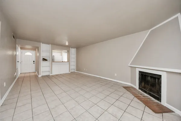 an empty room with windows and fireplace