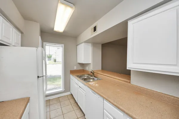 a kitchen with stainless steel appliances granite countertop a sink and white cabinets with a large window