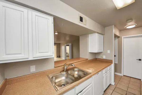 a kitchen with granite countertop a sink and white cabinets