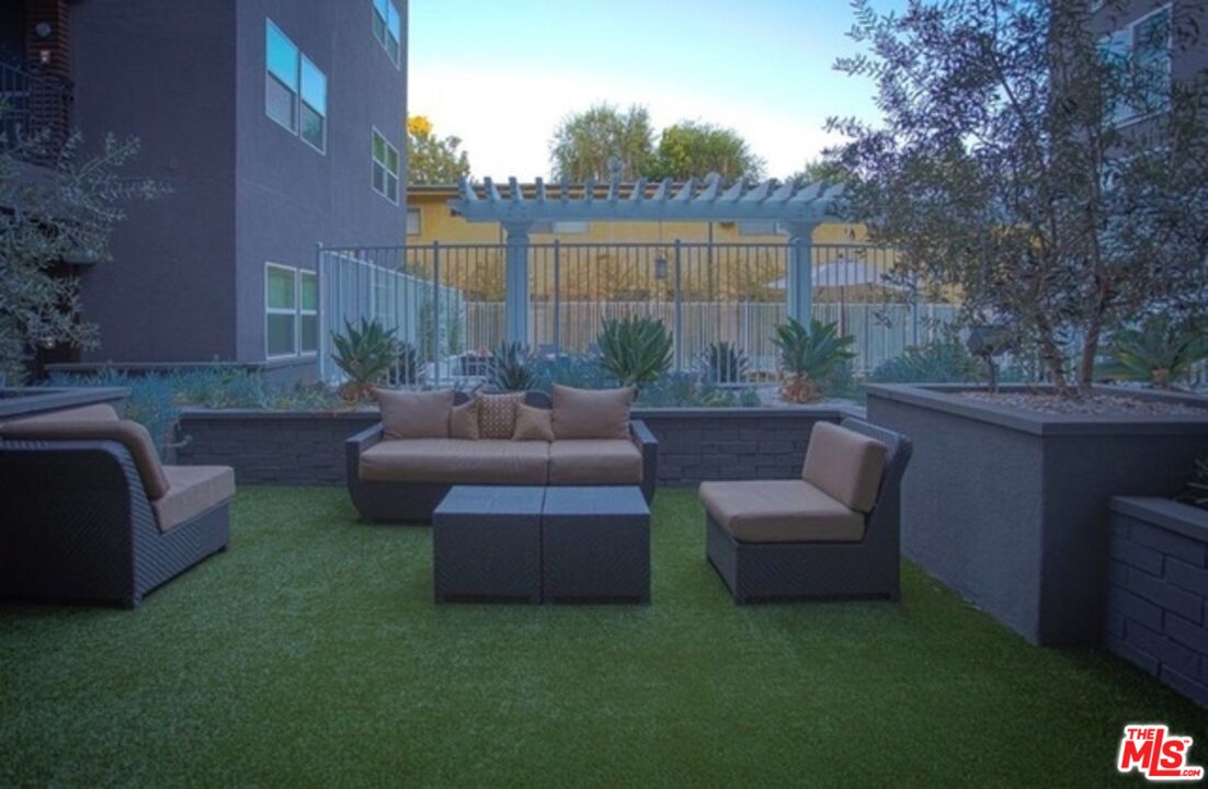 11925 Kling Street, Unit 311 Valley Village, CA 91607 - Photo 8 of 25 a view of a backyard with couches table and chairs with wooden fence