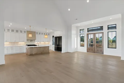 a large kitchen with kitchen island a stove a sink a center island and couches with wooden floor