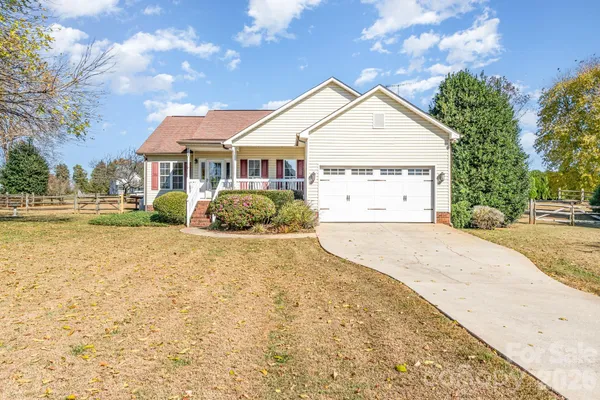 a view of a white house next to a yard with big trees