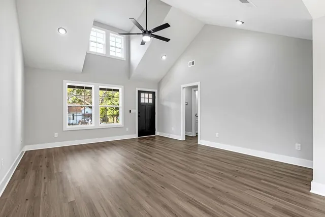 an empty room with wooden floor chandelier and windows