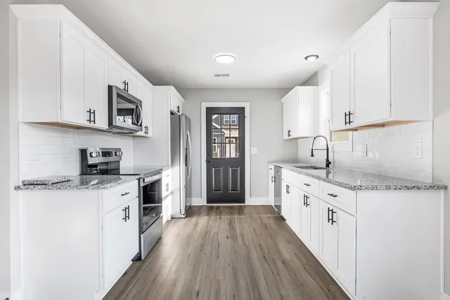 a kitchen with granite countertop a sink stove and cabinets