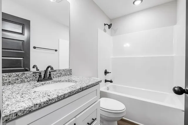a bathroom with a granite countertop sink a toilet and shower