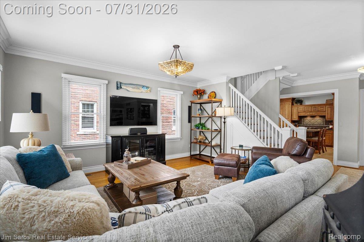 637 Washington Road Grosse Pointe, MI 48230 - Photo 9 of 40 Living area with wood-finish flooring, white crown molding, and a staircase featuring white risers and railings