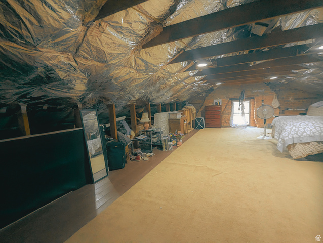 190 North 200 E Street Beaver, UT 84713 - Photo 40 of 40 Finished attic space featuring exposed wooden beams, foil-faced insulation, light gold carpeting, and built-in lighting