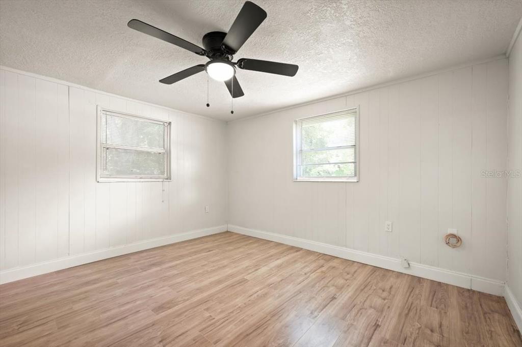 7903 New Kings Road Jacksonville, FL 32219 - Photo 22 of 28 an empty room with wooden floor ceiling fan and windows