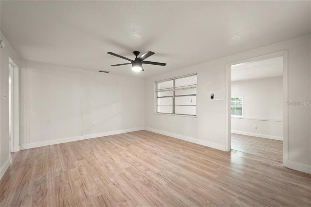 7903 New Kings Road Jacksonville, FL 32219 - Photo 6 of 28 an empty room with wooden floor chandelier fan and windows