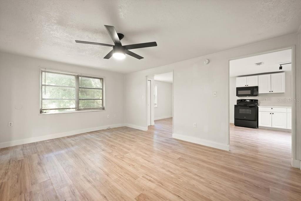 7903 New Kings Road Jacksonville, FL 32219 - Photo 8 of 28 an empty room with wooden floor a ceiling fan and windows