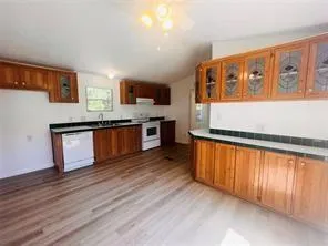 an empty room with wooden floor chandelier fan and windows