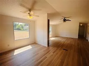 a view of a room with wooden floor and a ceiling fan