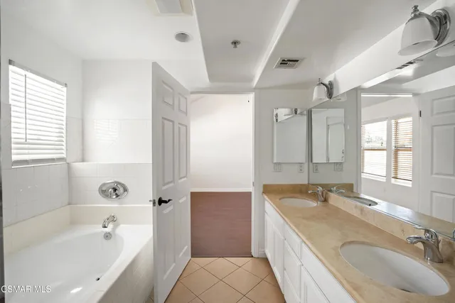 a bathroom with a granite countertop tub sink and mirror