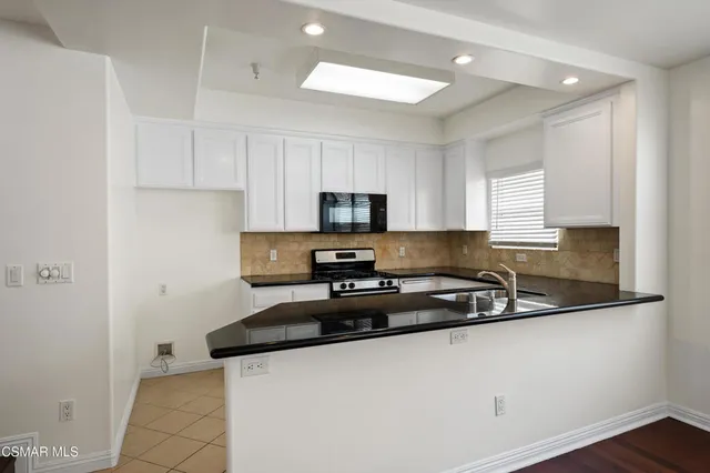 a kitchen with granite countertop a sink a stove and cabinets