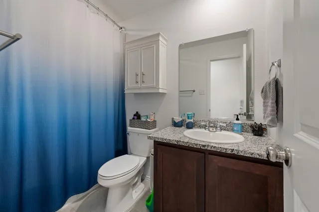 a bathroom with a granite countertop toilet sink and mirror