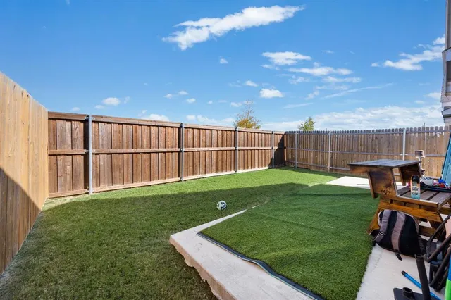 a view of a backyard with grass & fence