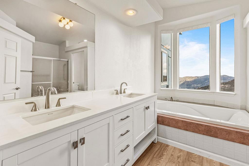 15351 Isla Vista Road Jamul, CA 91935 - Photo 32 of 40 a bathroom with a double vanity sink a large mirror and a bathtub