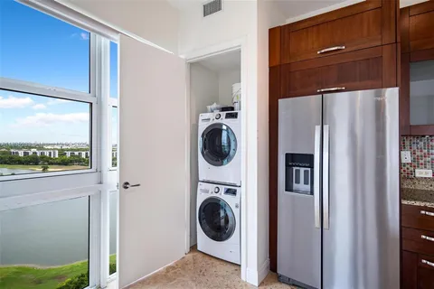 a view of a kitchen with kitchen island granite countertop a refrigerator a stove a sink and white cabinets with wooden floor