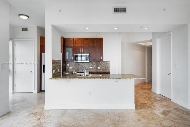 a large kitchen with a large counter top stainless steel appliances and cabinets