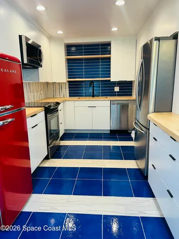 a kitchen with stainless steel appliances a rug and wooden cabinets
