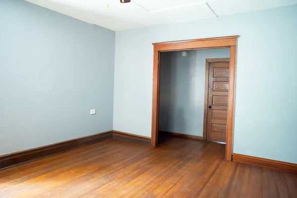 a view of an empty room with wooden floor and closet