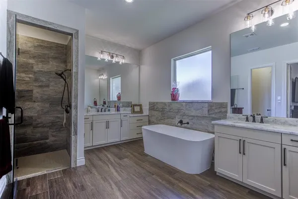 a bathroom with a bathtub shower sink and mirror