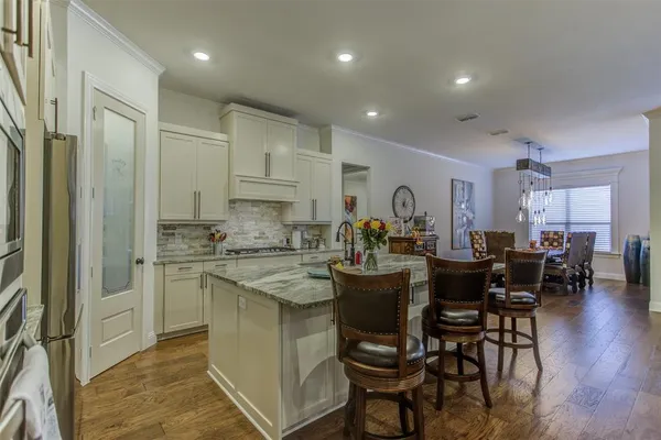 a kitchen with stainless steel appliances granite countertop a table chairs sink and cabinets