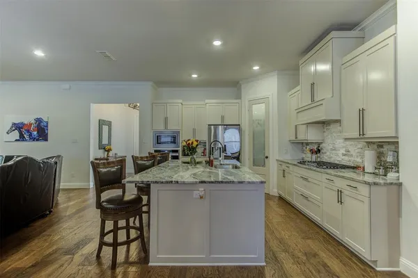 a kitchen with stainless steel appliances granite countertop a sink a stove a dining table and chairs