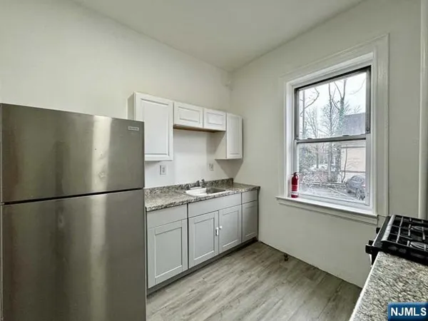 a kitchen with stainless steel appliances granite countertop a refrigerator a sink and a large window