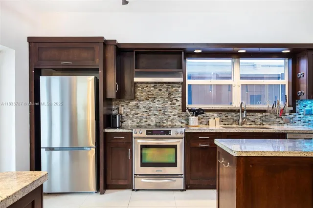 a kitchen with stainless steel appliances granite countertop a refrigerator and a stove