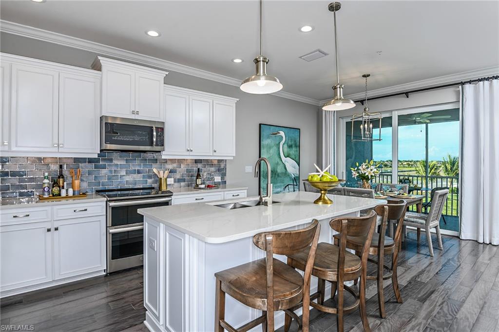 a kitchen with stainless steel appliances granite countertop a stove top oven a sink a stove a dining table and chairs with wooden floor