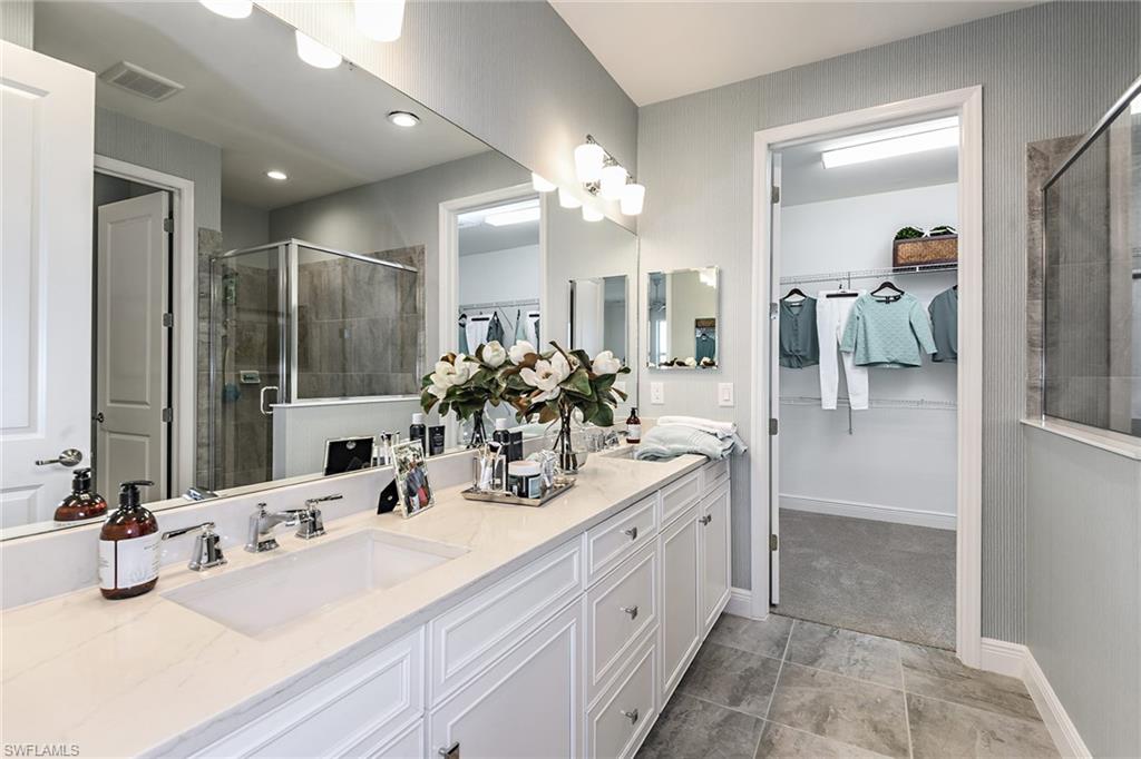2621 Seychelles Circle, Unit 1806 Naples, FL 34112 - Photo 11 of 25 a bathroom with double vanity sinks a vanity a mirror and shower