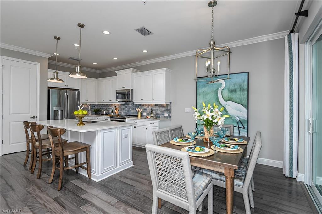 2621 Seychelles Circle, Unit 1806 Naples, FL 34112 - Photo 5 of 25 a kitchen with a dining table chairs stainless steel appliances and cabinets