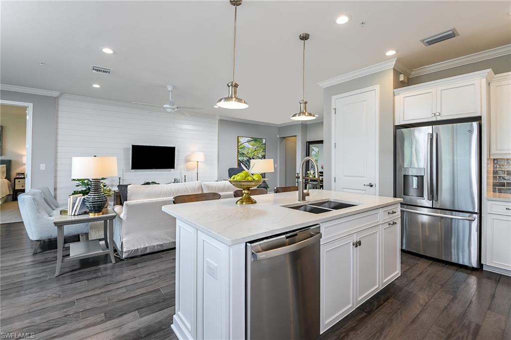 2621 Seychelles Circle, Unit 1806 Naples, FL 34112 - Photo 8 of 25 a kitchen with a sink stainless steel appliances and wooden floor