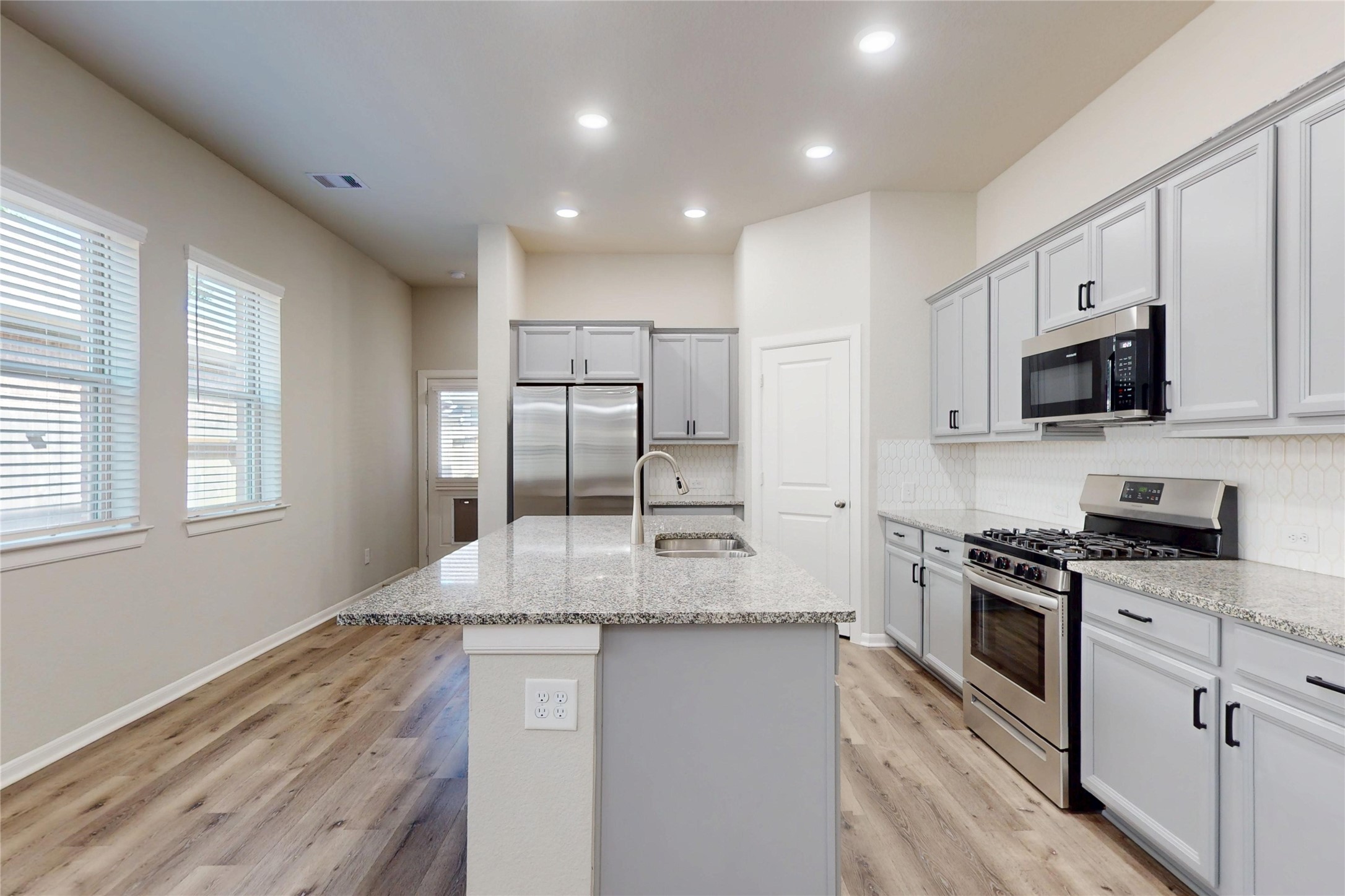 21586 Jordan Pond Ridge Porter, TX 77365 - Photo 8 of 30 A closer look at the kitchen- gas range & gas oven with microwave above. Fridge is included. Door to fully-bricked back covered patio with doggie door can be seen at back left.
