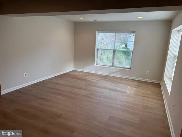 an empty room with wooden floor and a refrigerator