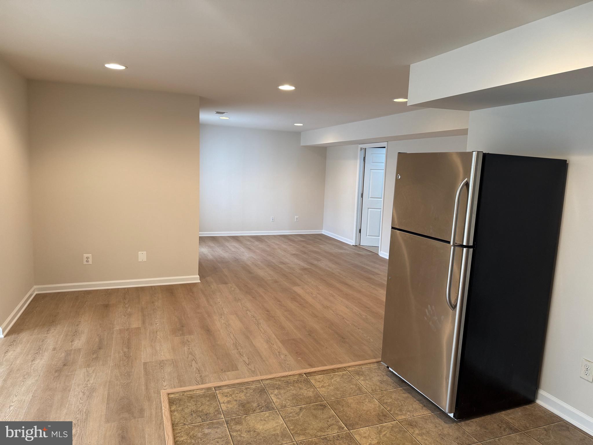 6231 Glen Wood Loop Manassas, VA 20112 - Photo 18 of 18 an empty room with wooden floor and a refrigerator