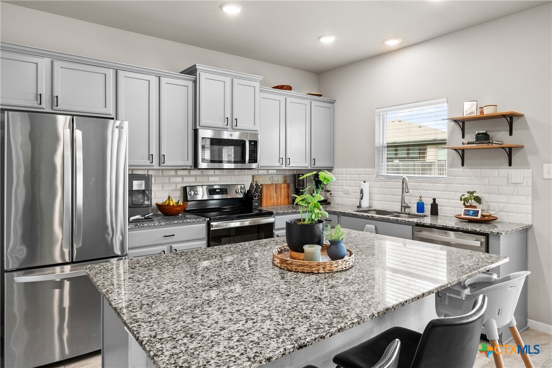 7468 Mossy Ridge Lane Temple, TX 76502 - Photo 11 of 38 a kitchen with stainless steel appliances granite countertop a refrigerator a stove a sink a dining table and chairs