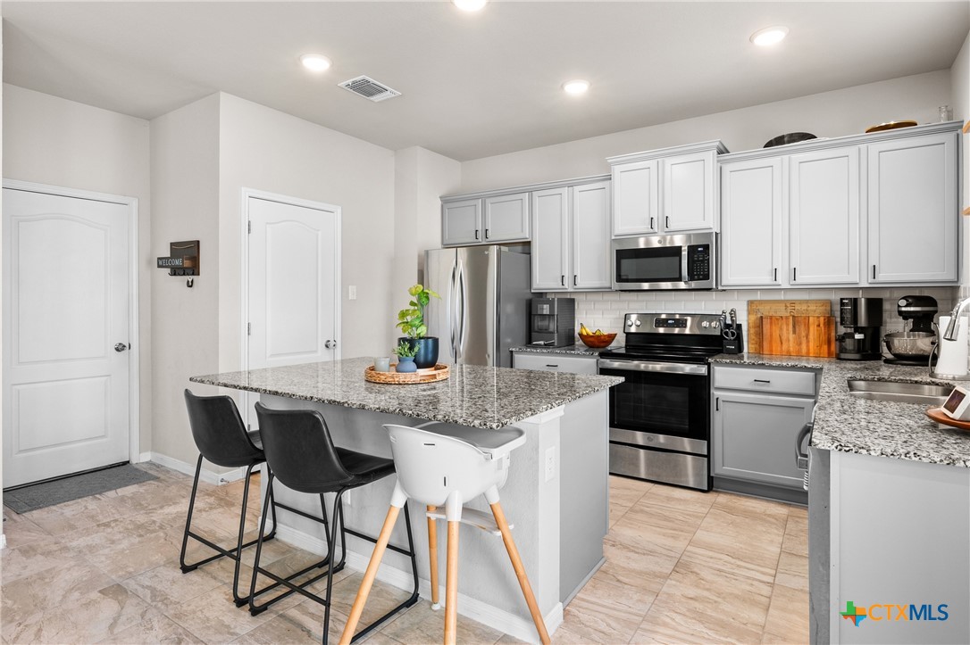 7468 Mossy Ridge Lane Temple, TX 76502 - Photo 15 of 38 a kitchen with stainless steel appliances granite countertop a stove a sink a microwave a refrigerator and white cabinets