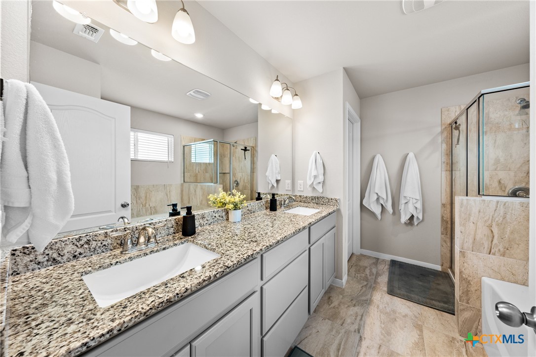 7468 Mossy Ridge Lane Temple, TX 76502 - Photo 20 of 38 a bathroom with a granite countertop sink a large mirror and a shower