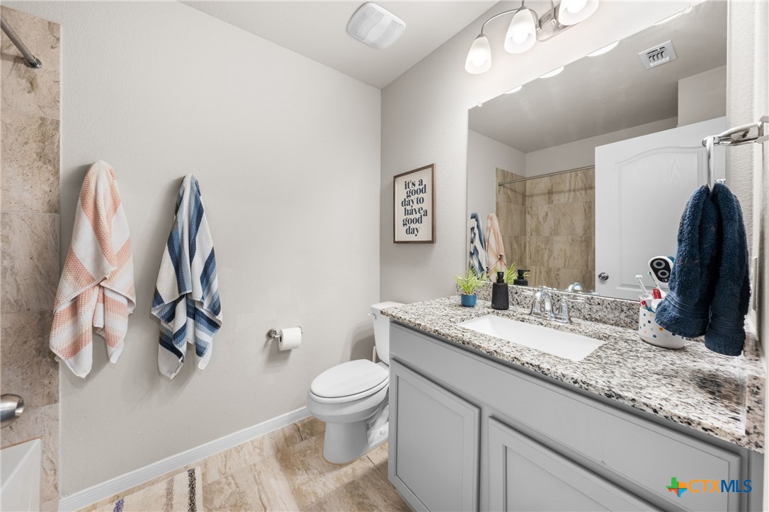 7468 Mossy Ridge Lane Temple, TX 76502 - Photo 27 of 38 a bathroom with a granite countertop sink vanity mirror and toilet